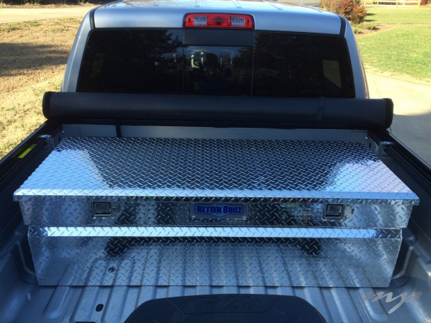 Tool box and rolled-up tonneau cover in front of truck bed.